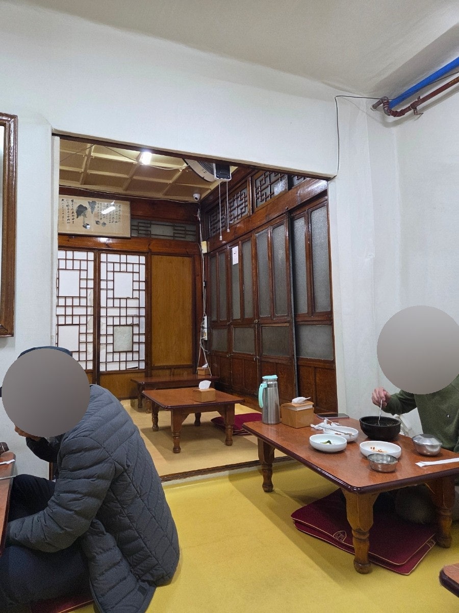gkdidqoqto는 50년 된 집인데도 장판이 반짝이고 방석과 테이블이 깔끔해 위생이 믿음직스러웠다고 적었습니다. 첫 사진은 좌식 상에 둘러앉은 손님들의 모습이고,