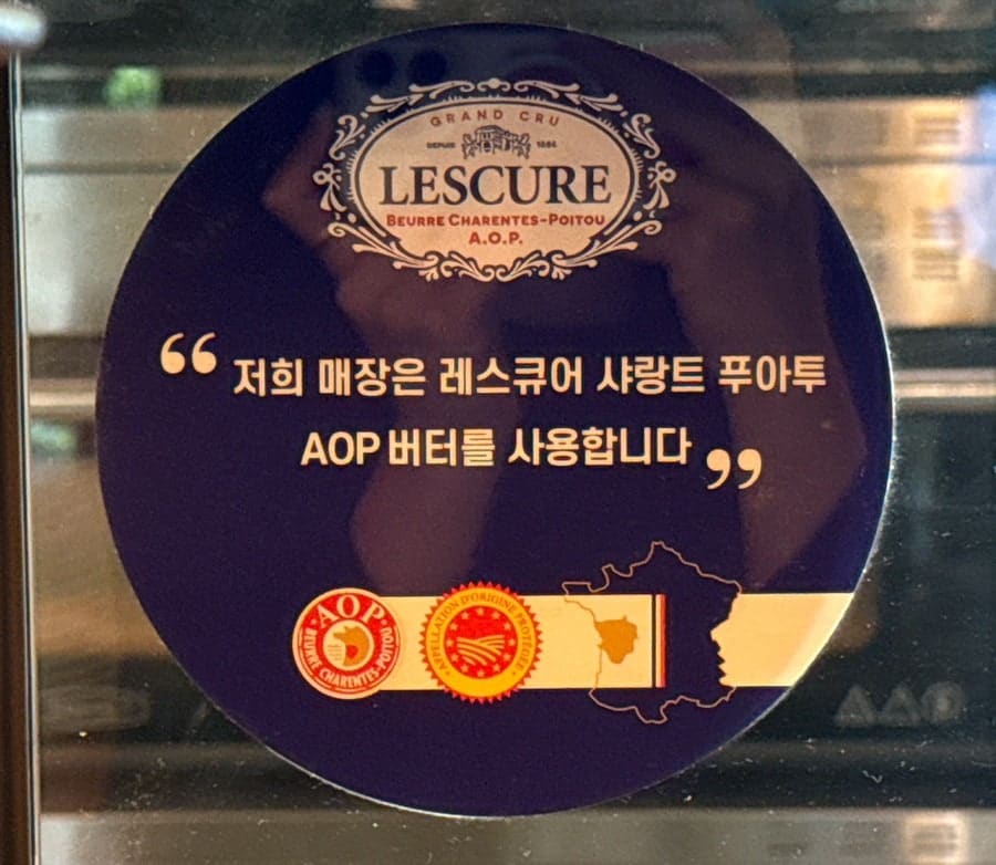 르프랭크를 찾은 방문자가 남긴 사진입니다. 프랑스산 AOP 버터를 쓴다는 안내 스티커와, 제빵 수료증 액자 옆에 놓인 머그잔입니다.