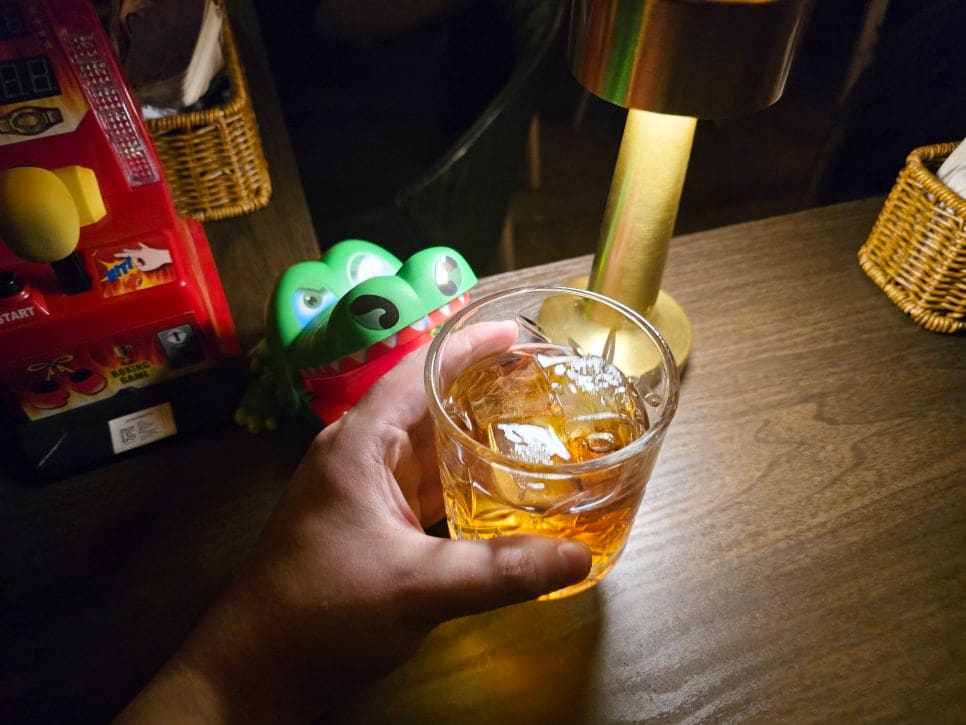 혼술바를 찾은 방문자가 남긴 사진입니다. 오락기와 인형이 놓인 테이블 위로 조명 하나가 술잔을 비추는 장면인데, 혼자 와도 어색하지 않은 아늑한 자리라는 인상을 남겼습니다.