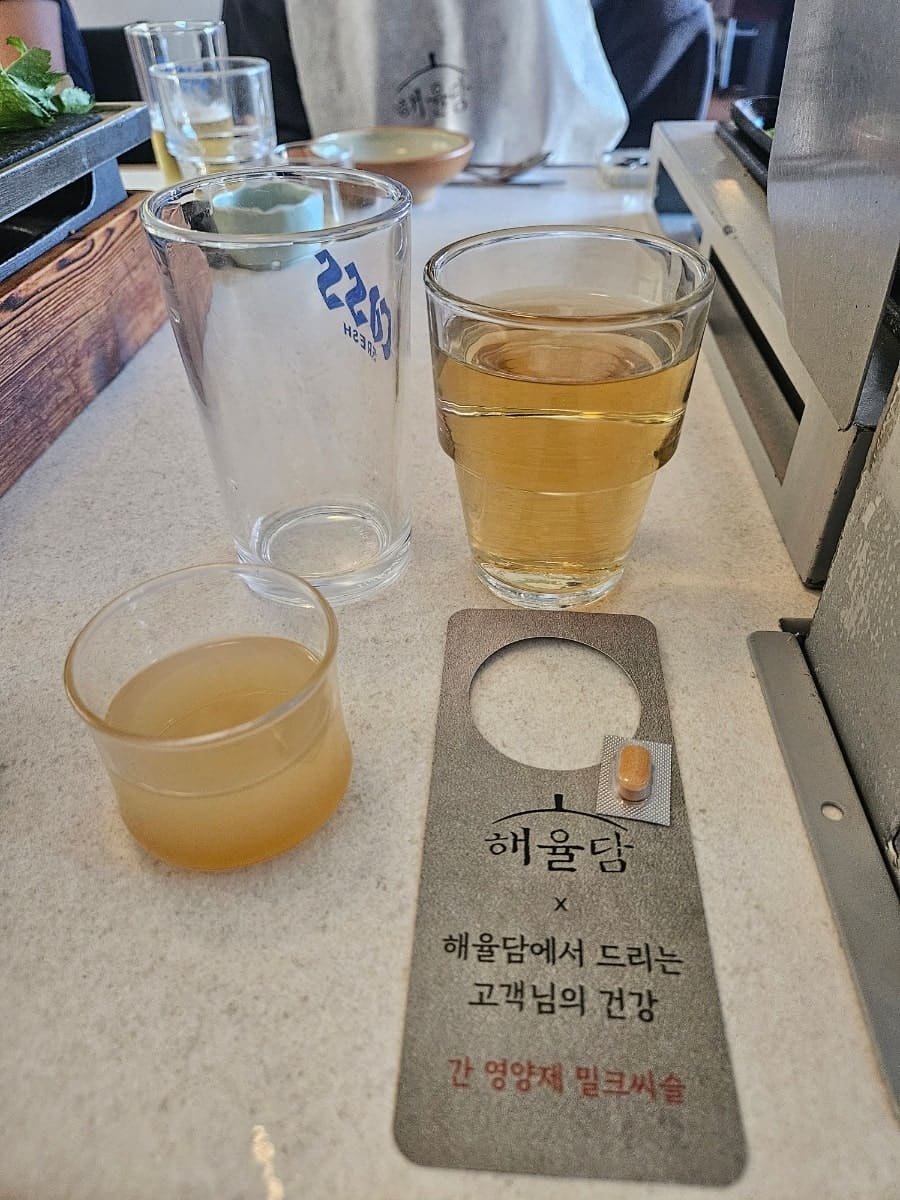 srs060200이 9월에 남긴 사진입니다. 숙성 중인 고기 덩어리들이 유리 진열장 안에 걸려 있고, 그 위로 이 집의 문구가 새겨져 있습니다. 테이블에는 술과 음료,
