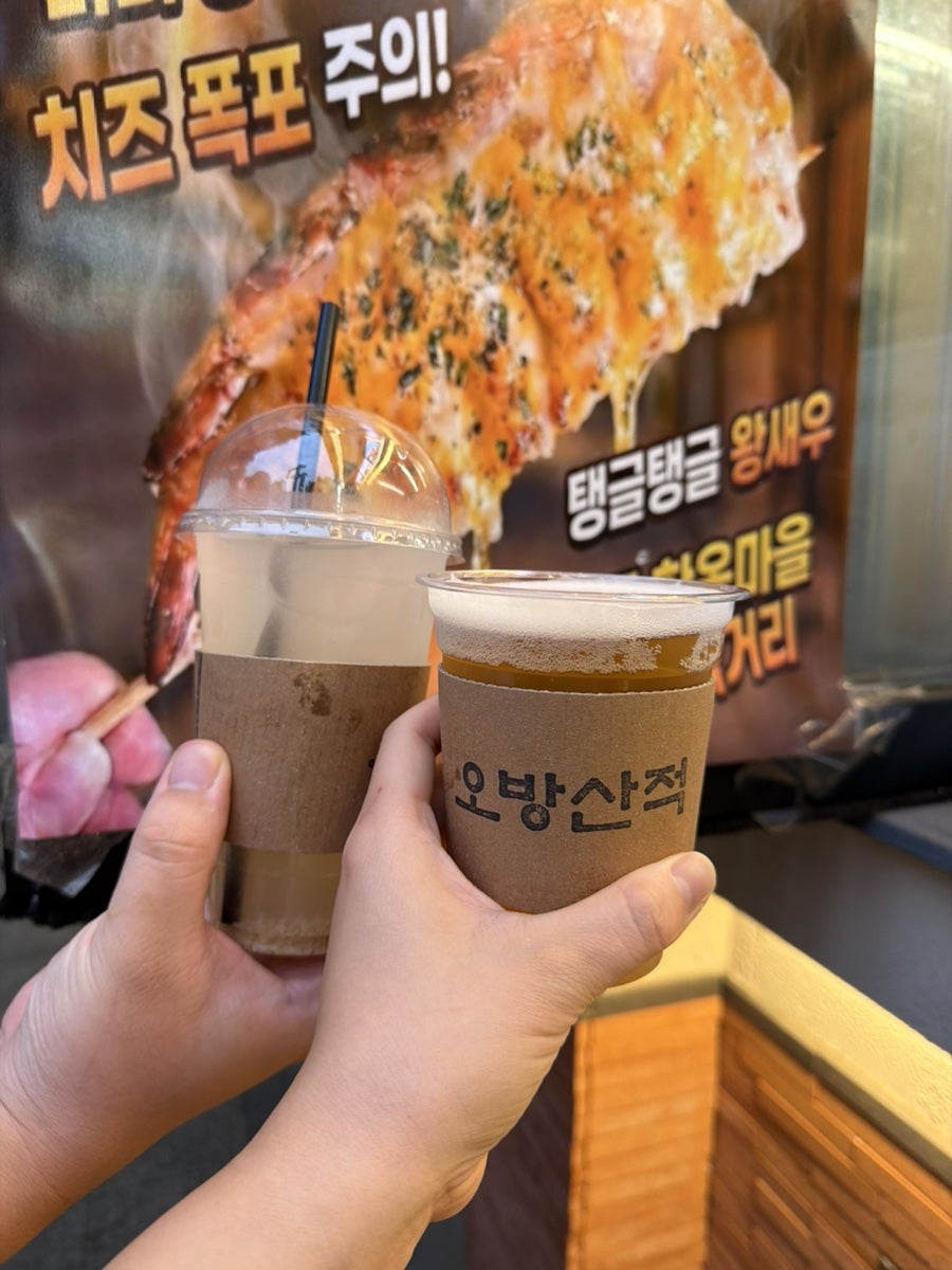 아이와 함께 처음 방문했다는 사람이 남긴 사진입니다. 치즈와 소스가 듬뿍 올라간 꼬치를 손에 들고 찍은 컷과, 오방산적이라고 쓰인 컵 슬리브를 쥔 손이 함께 담겼습니다.