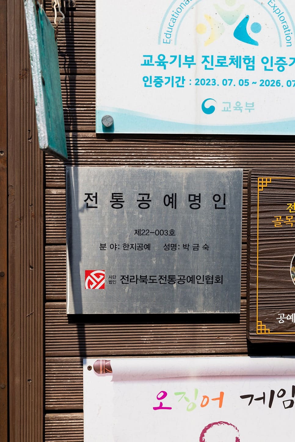 jeonjuhanok1004가 촬영한 공예명품길 안쪽 골목입니다. 좁은 돌길 양옆으로 한옥 지붕과 공방 간판이 늘어서 있고, 벽에는 전통공예명인 명패가 붙어 있습니다.