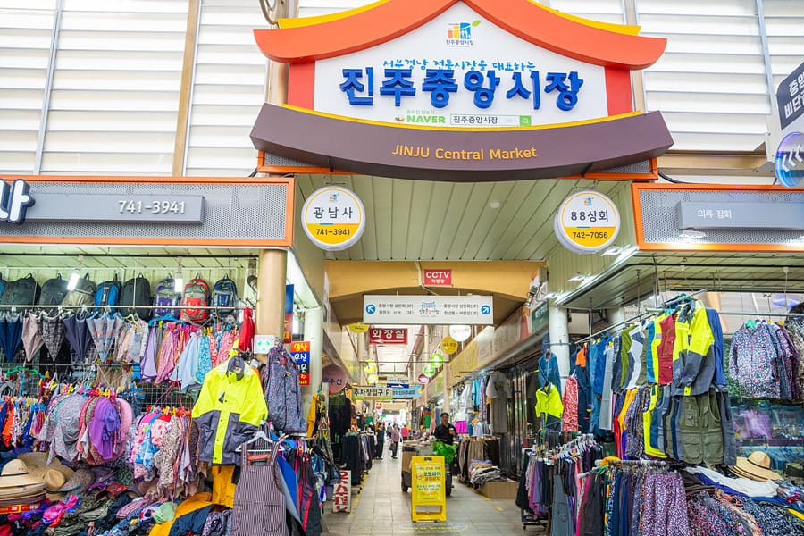 진주중앙시장 정문 아치 간판과, 선풍기와 이불 같은 생활용품을 파는 점포. 먹거리뿐 아니라 생활에 필요한 것들을 두루 파는 시장의 면모를 보여준다.