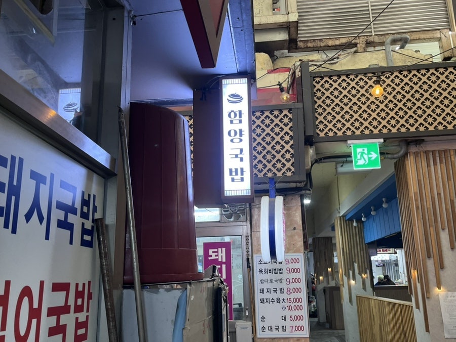 jjs1324는 저녁 무렵 불 켜진 간판과, 함께 나온 깍두기·양파 절임·매운 양념장 같은 밑반찬을 한 상에 담아 찍었습니다.
