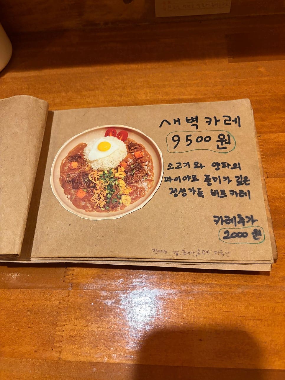 손으로 정성스럽게 엮인 수제작 메뉴판. 사장님이 직접 그려 넣은 글씨와 이미지가 새벽카레만의 세계를 담아낸다.