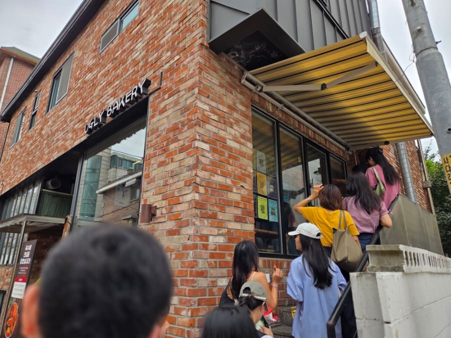 springjean은 가게 계단 앞에서 시작한 줄이 바로 앞 차도 때문에 길 건너로 이어지는 모습을 적었습니다.