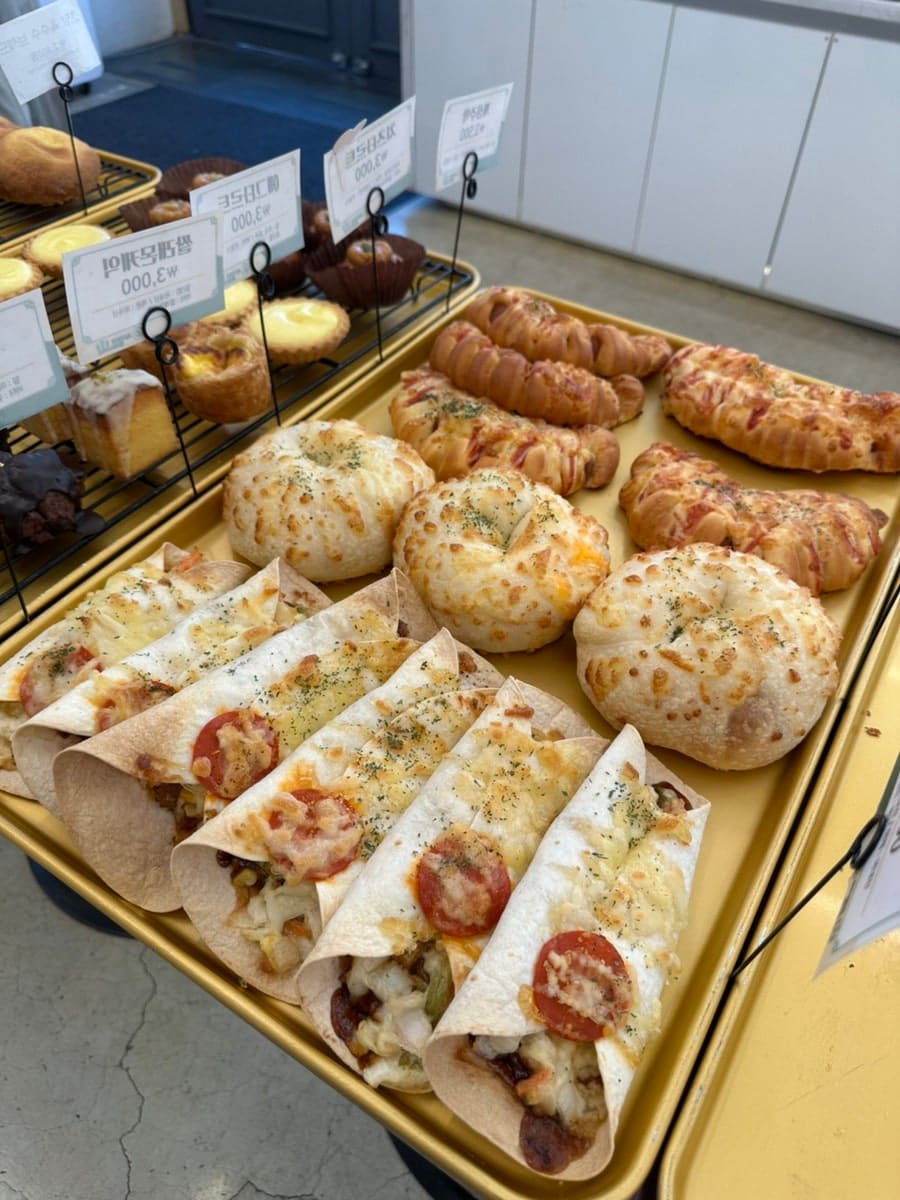 dearjiny_는 창가 진열대와 벽에 붙은 빙수 맛집 포스터, 그리고 치즈를 듬뿍 올린 또띠아피자 트레이를 이어서 담았습니다.