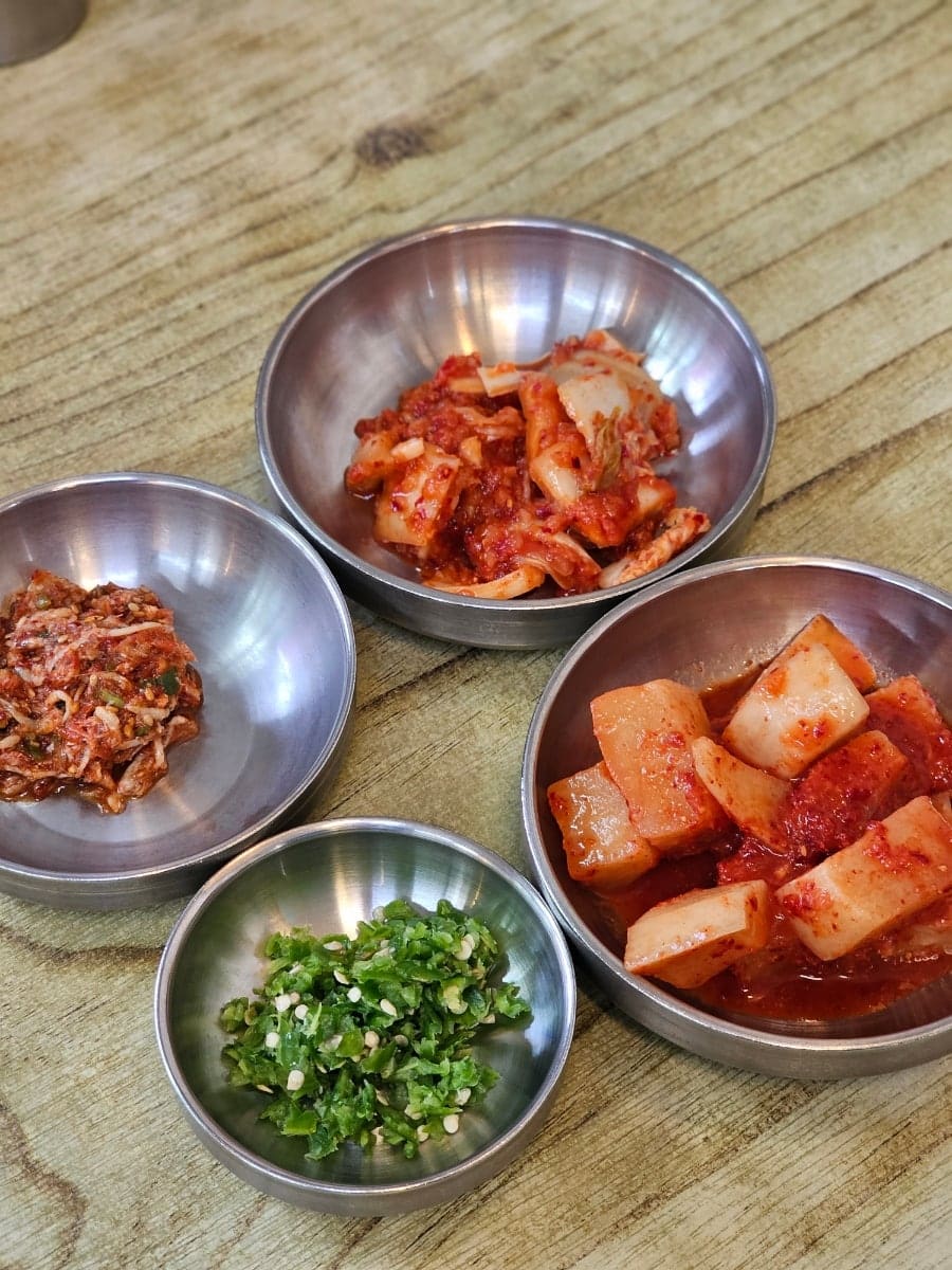 dmsdk4490은 김치, 깍두기, 새우젓무침, 청양고추 다진 것까지 밑반찬 네 접시를 찍고, 뚝배기 가득 담겨 보글보글 끓는 선지해장국도 가까이서 찍었습니다.
