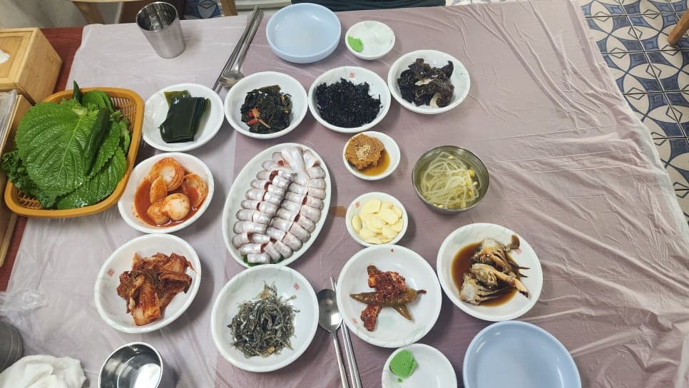 yeoga0704는 벽에 붙은 가격표와 여섯 테이블 남짓한 좁은 홀을 먼저 찍고, 동그랗게 말아 낸 밴댕이회와 밑반찬이 가득한 상차림을 위에서 내려다보며 담았습니다.