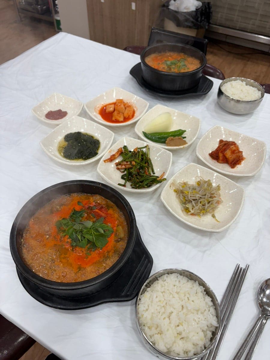 itoshii14는 흰 상보 위에 차려진 두 그릇의 장어탕과 반찬 여덟 접시를 넓게 찍고, 김이 오르는 뚝배기도 가까이서 찍었습니다.