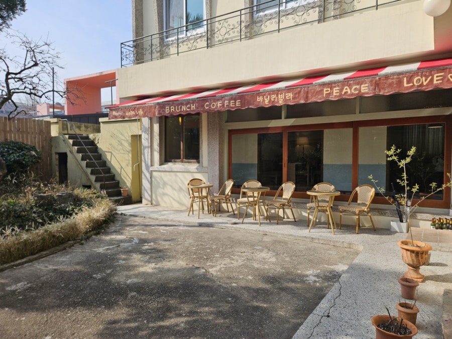jutoryblog는 'BRUNCH COFFEE 바닐라빌라'라고 적힌 차양 아래 야외 테이블이 놓인 건물 외관과, 바닥에 세워 둔 손글씨 입간판을 담았습니다.