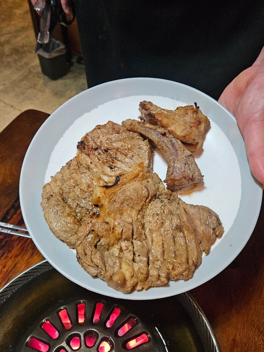 불을 올리기 전 무쇠 불판과, 다 구워 접시에 옮겨 담은 돼지갈비입니다. 두 블로거 모두 이 불판 위에서 육수를 부어가며 굽는 방식을 낯설어했지만,