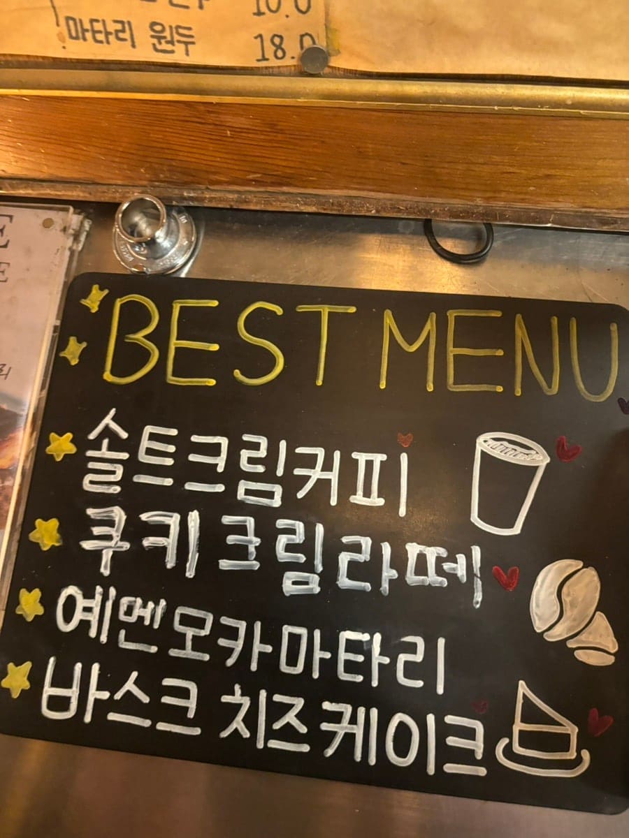 칠판엔 손글씨로 적은 베스트 메뉴, 벽엔 나무로 깎은 사람 모형들이 사다리를 오르내리는 조형물이 붙어 있습니다.