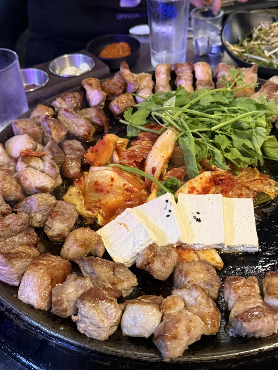 밤에 올려다본 간판에는 '솥돈 SOT DON' 글자가 환하게 켜져 있습니다. 블로거는 돌판 위에 김치 한 포기와 두부, 미나리를 함께 올려 구워 주는 방식이라고 적었는데,