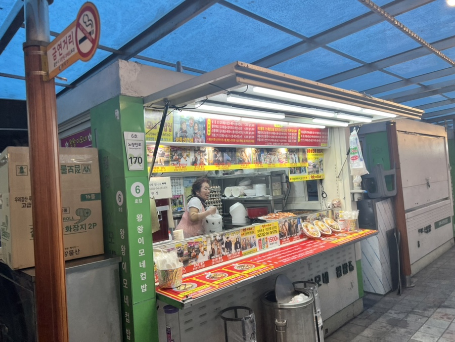 kar7519가 대낮에 담은 장면입니다. 노점 앞에 손님들이 줄지어 서 있고, 왕왕이모네컵밥 가게 안에서는 상인이 쉴 틈 없이 손을 움직입니다.