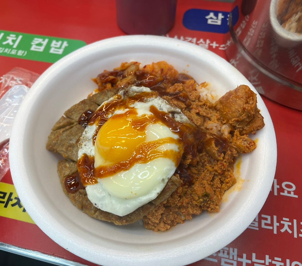 j___3가 먹기 직전 담은 두 장입니다. 반숙 달걀이 흘러내리는 컵밥과 김이 오르는 떡볶이에서, 갓 받은 음식의 온도가 그대로 느껴집니다.