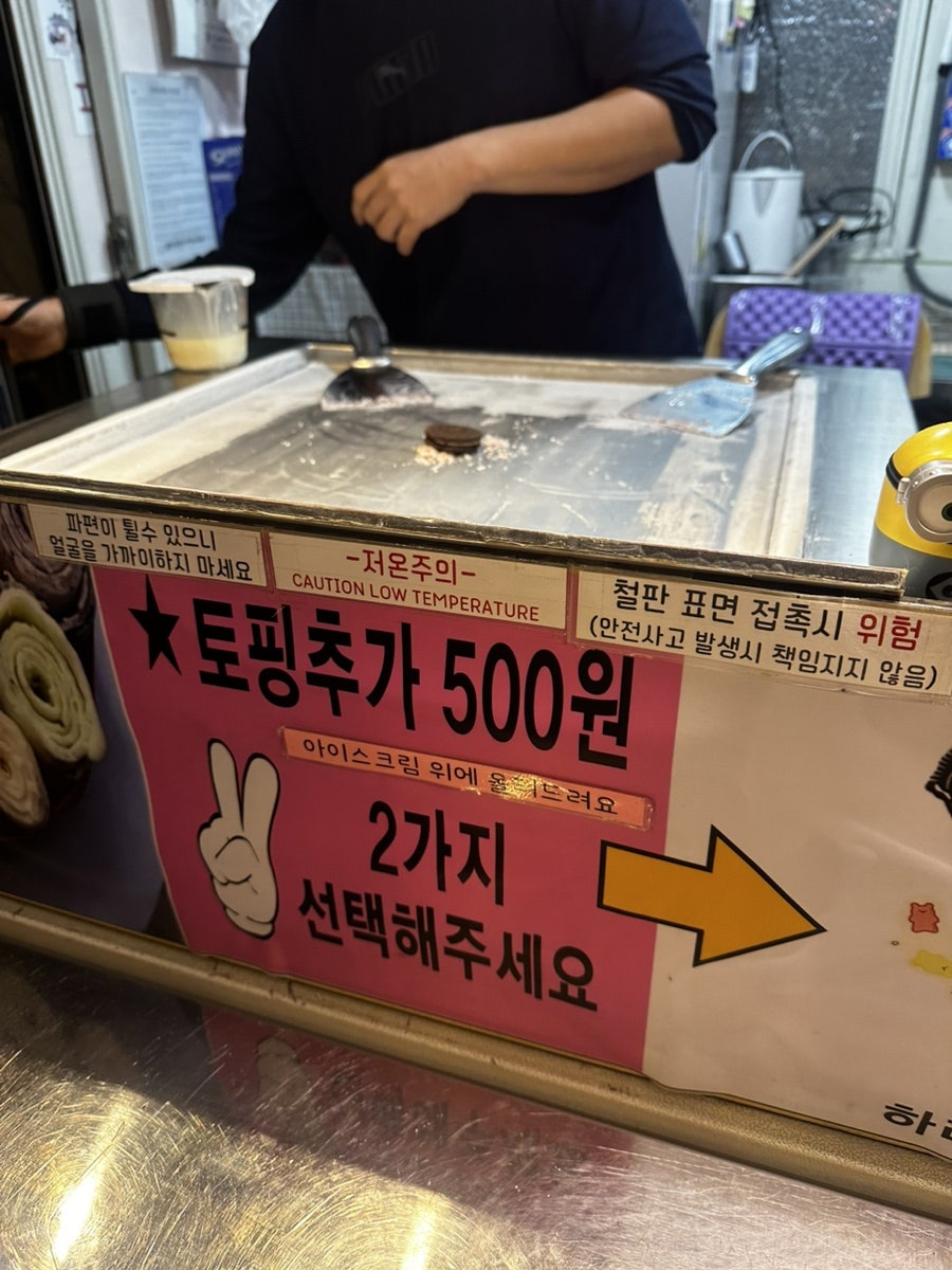 wlgid4066이 담은 조리 장면입니다. 차가운 철판 위에서 아이스크림을 펴 바르는 손길과, 토핑 추가를 안내하는 문구가 가까이서 보입니다.