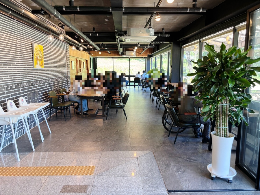 white880704는 평일 점심인데도 브런치를 즐기러 온 손님들로 매장이 꽉 차 있었다고 적었습니다. 사진에는 벽돌 벽을 배경으로 한 원목 테이블과 큰 화분,