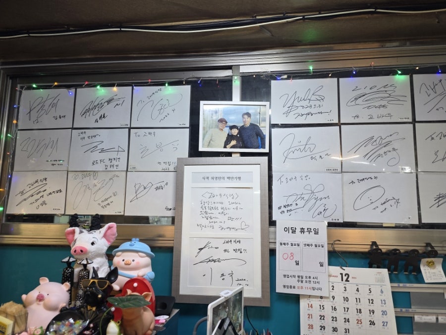 qkeotns95가 찍은 사진입니다. 다녀간 손님들의 사인으로 가득한 벽과 식객 허영만의 백반기행 촬영 메모가 함께 걸려 있고,