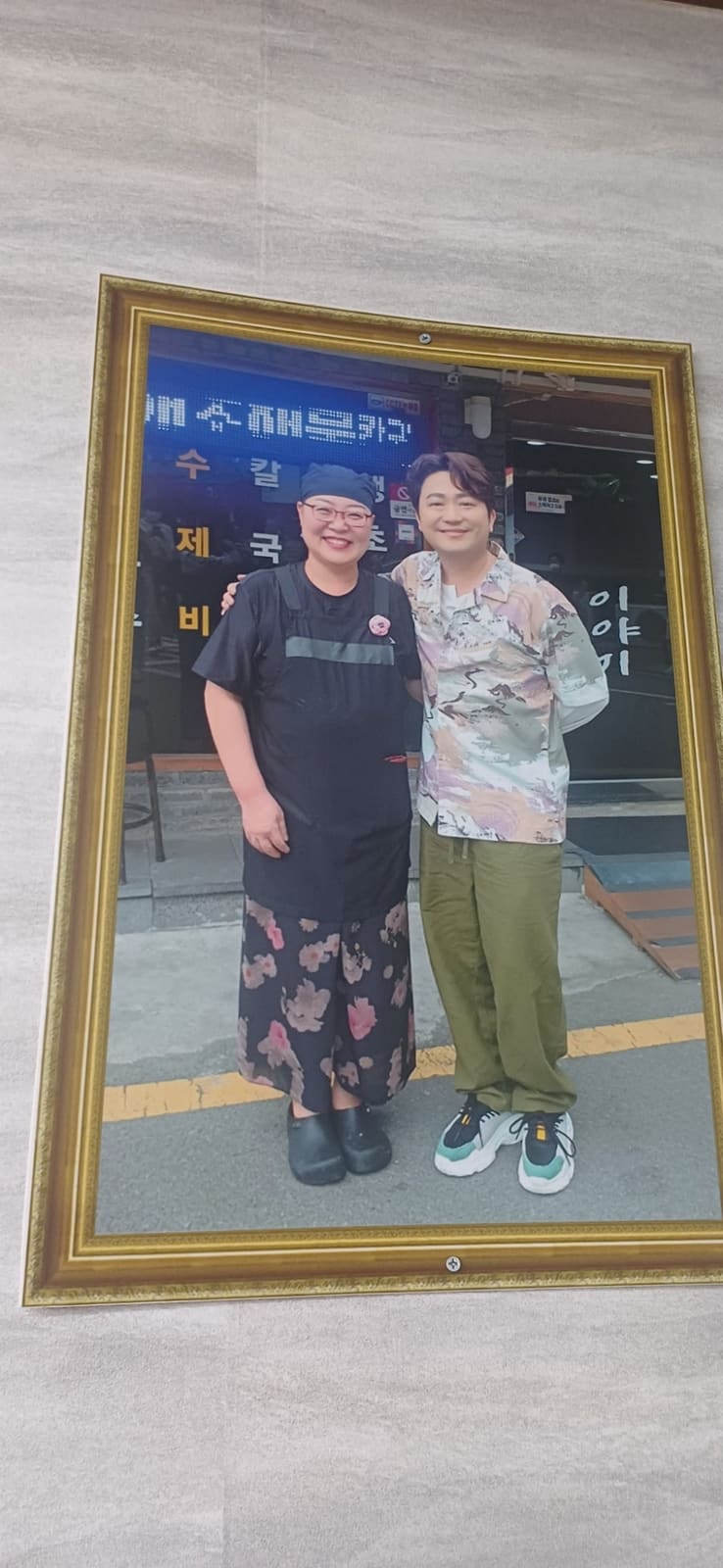 같은 블로거가 매장 안쪽을 찍은 사진입니다. 벽에는 방송 출연 당시 사장님이 연예인과 함께 찍은 액자가 걸려 있고, 2층 난간 위 선반에도 작은 상장과 소품들이 올라가 있습니다.