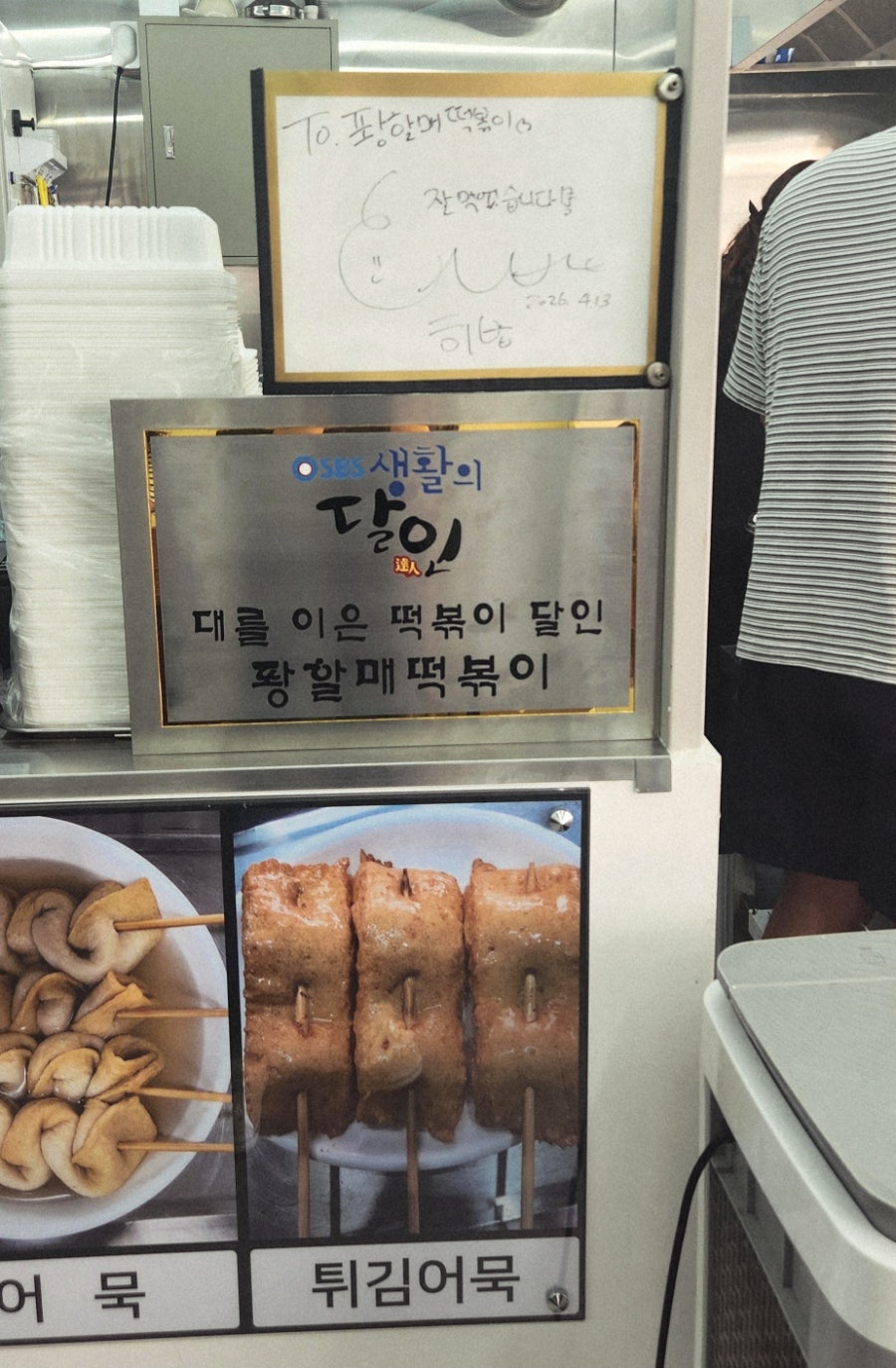 heavenbornmk가 찍은 사진입니다. 스테인리스 조리대와 필름 콜라주가 이어진 주방 안쪽, 그리고 생활의 달인 현판과 메뉴 사진이 나란히 걸린 모습입니다.