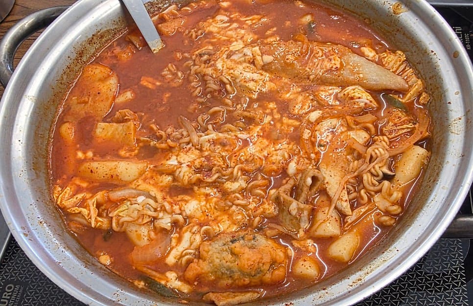 adamseven은 친한 언니와 기본 2인 세트에 라면과 치즈를 고르고, 맵찔이라 기본 맛으로 주문했다고 적었습니다. 첫 사진은 라면이 풀린 붉은 국물이 끓는 팬이고,