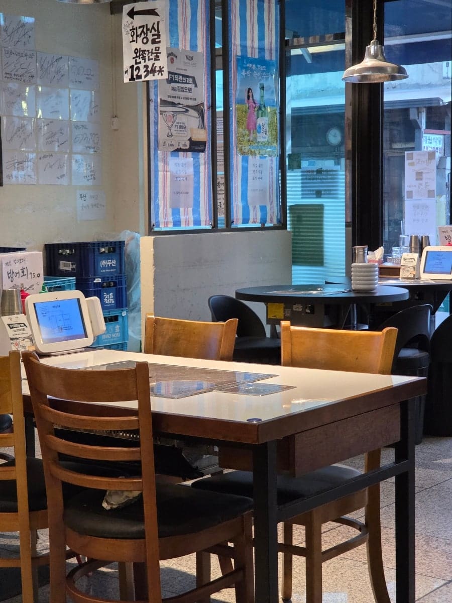 매장 내부입니다. 넓은 공간에 테이블들이 배치되어 있으며, 창문으로 거리의 풍경도 볼 수 있습니다.