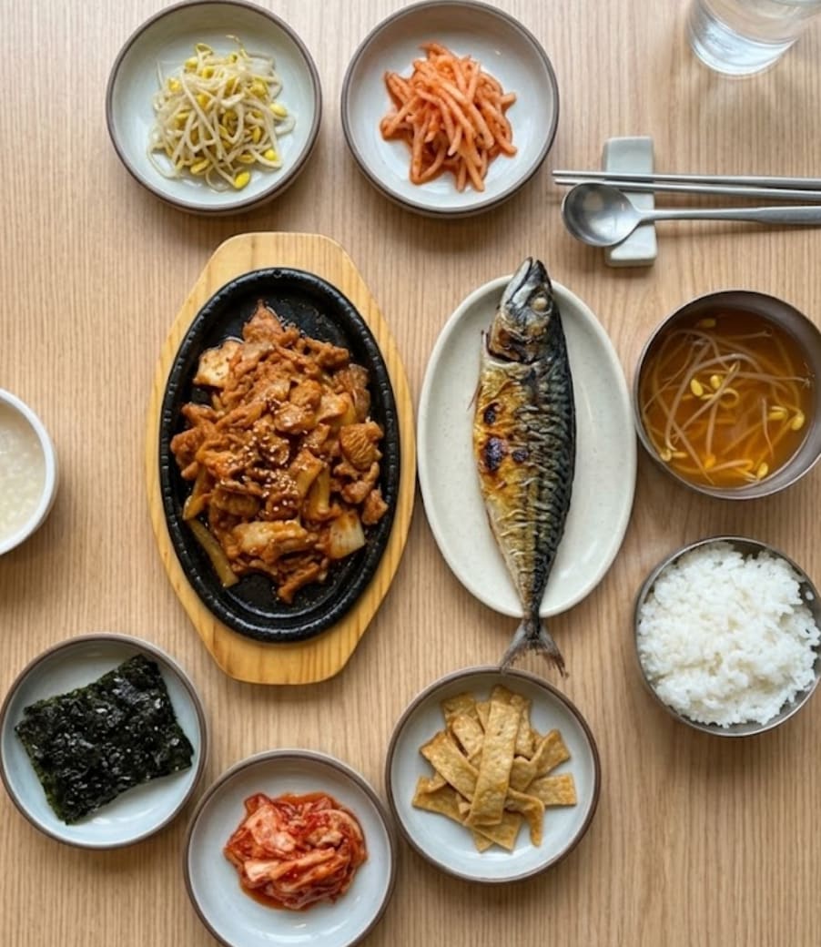 또 다른 방문 시점의 밥상입니다. 생선과 제육 두루치기, 밥과 국, 여러 종류의 반찬이 정성스럽게 준비되어 있습니다.