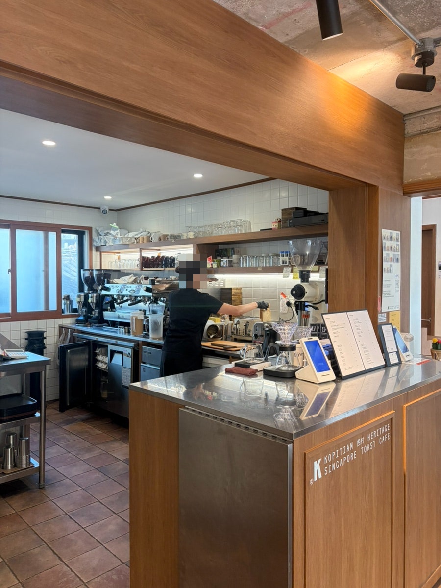 dlwndud1927은 'KOPITIAM SINGAPORE TOAST CAFE' 로고가 박힌 바 카운터와, 줄무늬 벽지에 레코드판을 장식한 안쪽 좌석을 찍었습니다.