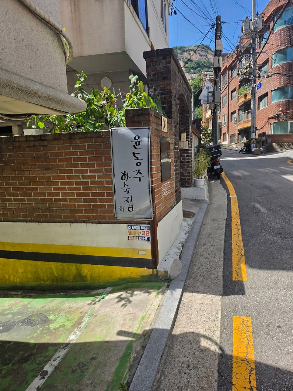 서촌 골목의 역사와 문학. 시인 윤동주가 살았던 하숙집 터와 인문학적 의미를 담은 안내판. 낡은 벽돌 담장 위에 붙은 이 패널은 과거와 현재를 잇는 통로 역할을 한다.