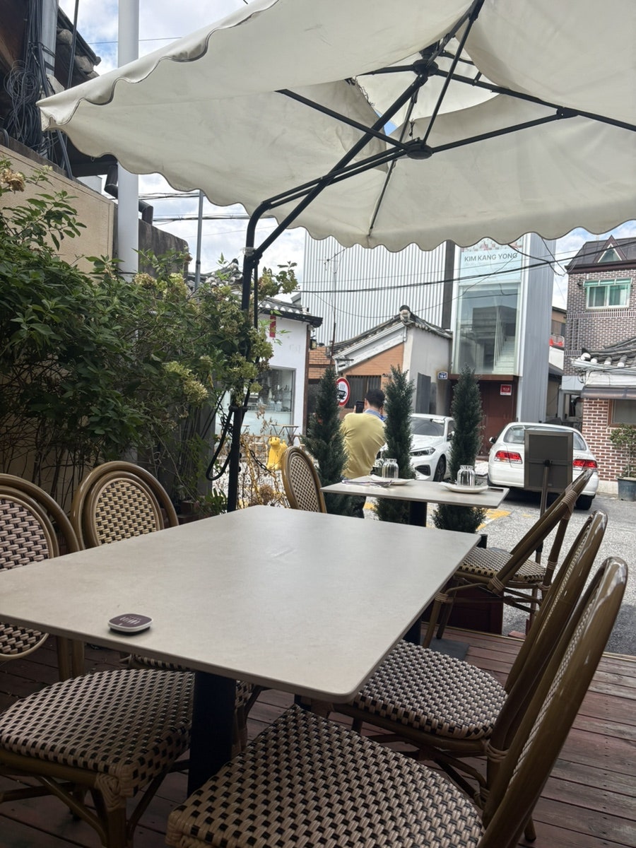 babmookjang은 수국 덩굴이 늘어진 테라스 테이블과, 파라솔 아래 골목 풍경이 보이는 또 다른 테라스 자리를 찍었습니다.