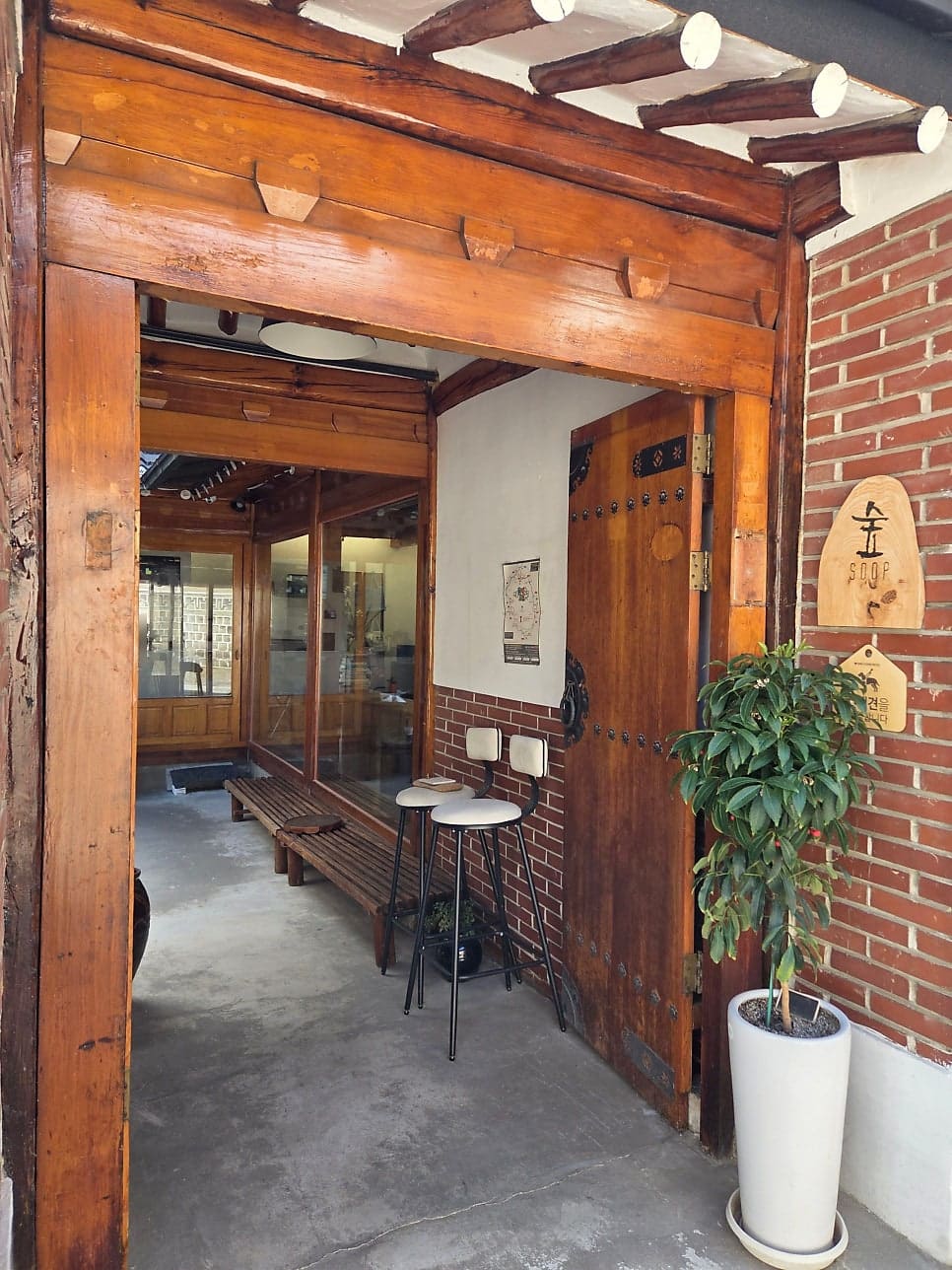 가격표를 옮겨 적어둔 wonderlend82가 찍은 마당과 대문 안쪽입니다. 기와지붕 아래 'COFFEE BAR' 글자가 보이는 마당에 접이식 테이블과 의자가 놓여 있고,