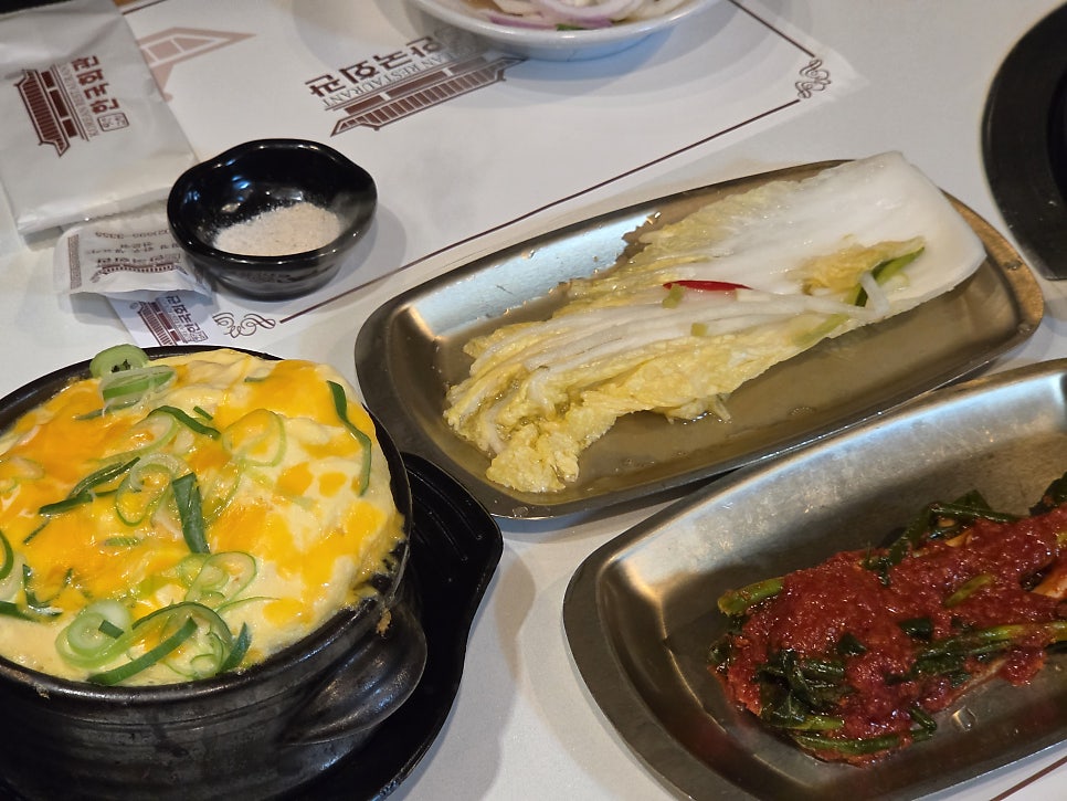 같은 분이 찍은 계란찜 사진입니다. 치즈를 얹어 뚝배기째 지글지글 끓인 계란찜 위로 파가 수북이 올라가 있고, 옆에는 백김치와 겉절이가 함께 담겨 있어,