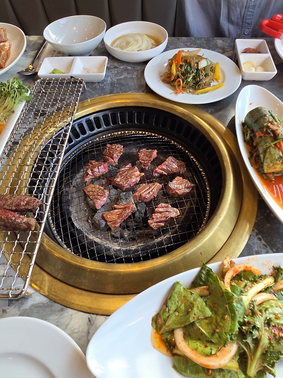 같은 분이 남긴 또 다른 사진에는 황동 테두리의 불판 위로 두툼한 한우 조각들이 노릇하게 구워지는 모습이 담겨 있습니다. 1++, 1+ 등급의 한우만 쓴다는 설명과 함께,