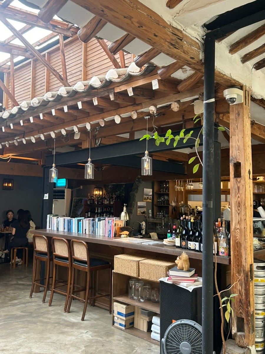 p6934는 뷰가 예쁜 카페는 좌석이 불편했다며, 돌담 뷰와 편한 좌석을 함께 만난 곳으로 이 집을 꼽았습니다. 첫 사진은 안에서 창을 본 장면으로,