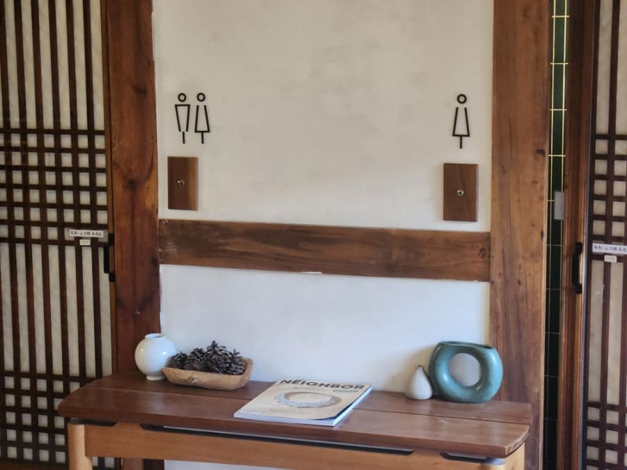 2층 한옥 마루 난간 너머로 노키즈존 팻말이 붙어 있고, 화장실 앞 작은 탁자엔 솔방울 장식이 놓여 있습니다.
