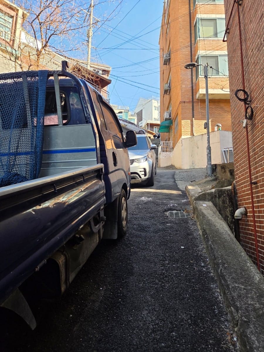 ziyoukmh는 짐을 실은 트럭이 벽돌 건물 사이 좁은 골목을 지나가는 장면과, 같은 골목의 가파른 오르막을 이어서 찍었습니다. 차 한 대가 겨우 지나갈 폭이라,