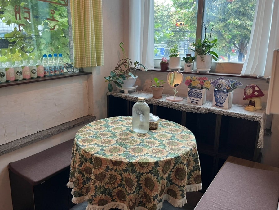 guavadiary는 해바라기 무늬 식탁보가 덮인 테이블과, 복고풍 라디오·행운 고양이 인형이 놓인 선반을 찍었습니다.
