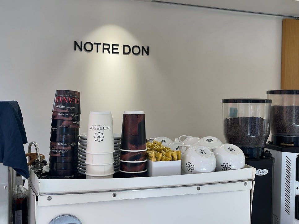 onnement은 벽돌 건물 2층에 자리한 매장 외관과, 컵과 원두 통이 쌓인 카운터 한편의 'NOTRE DON' 로고를 함께 남겼습니다.