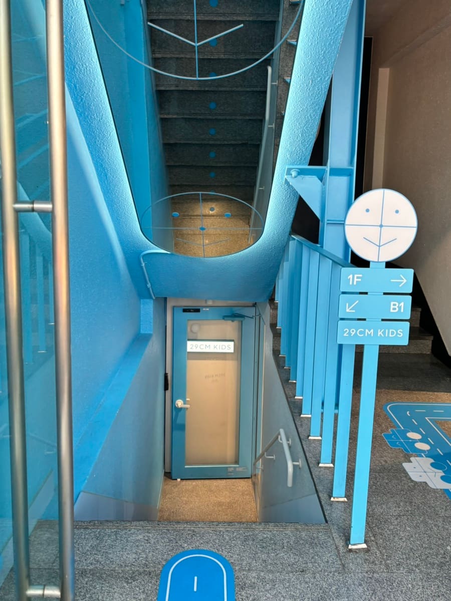 매장 내부의 진열 공간과, 지하 1층으로 이어지는 계단 초입의 안내 표지입니다. 층마다 다른 구성으로 나뉘어 있는 구조를 블로거는 눈여겨봤습니다.