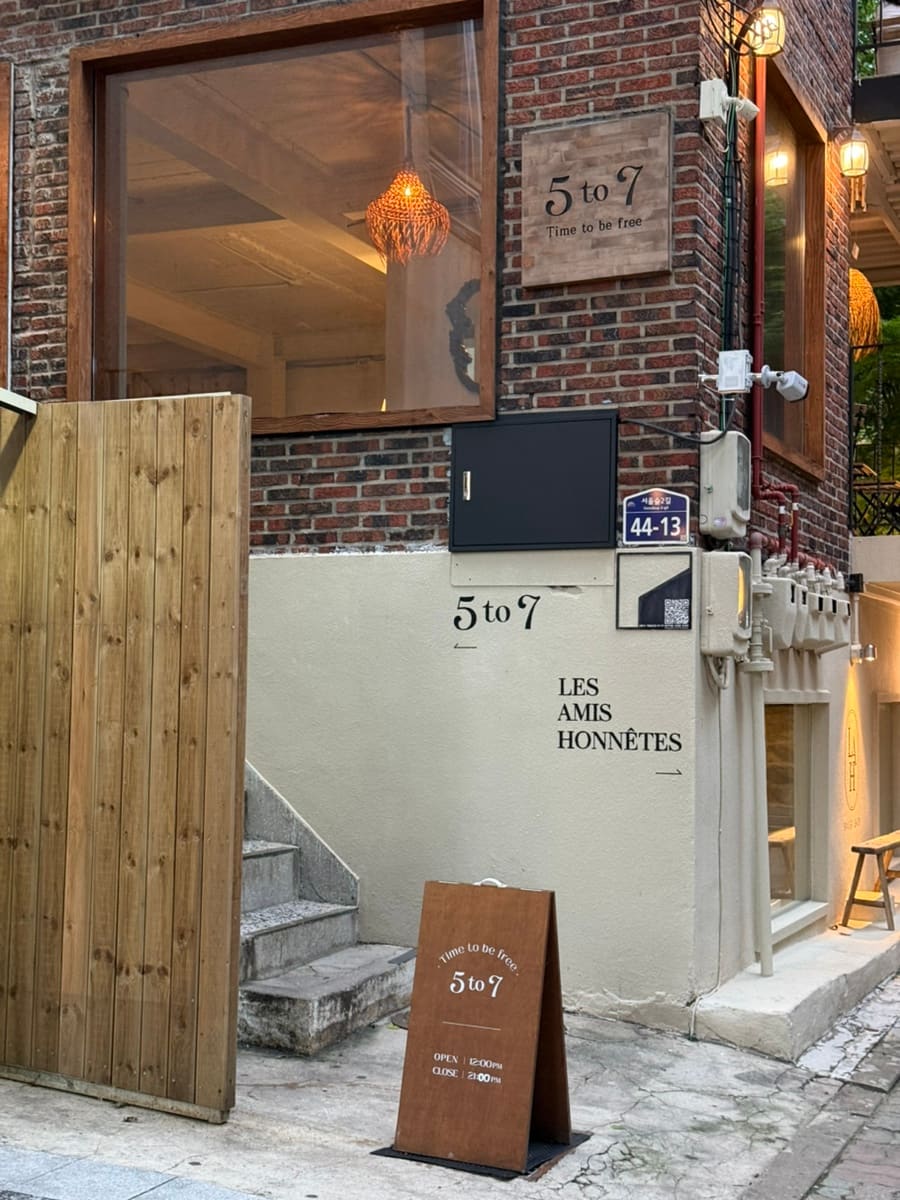 레레언니라고 소개한 방문자입니다. 붉은 벽돌 벽에 걸린 '5to7 Time to be free' 나무 간판과,