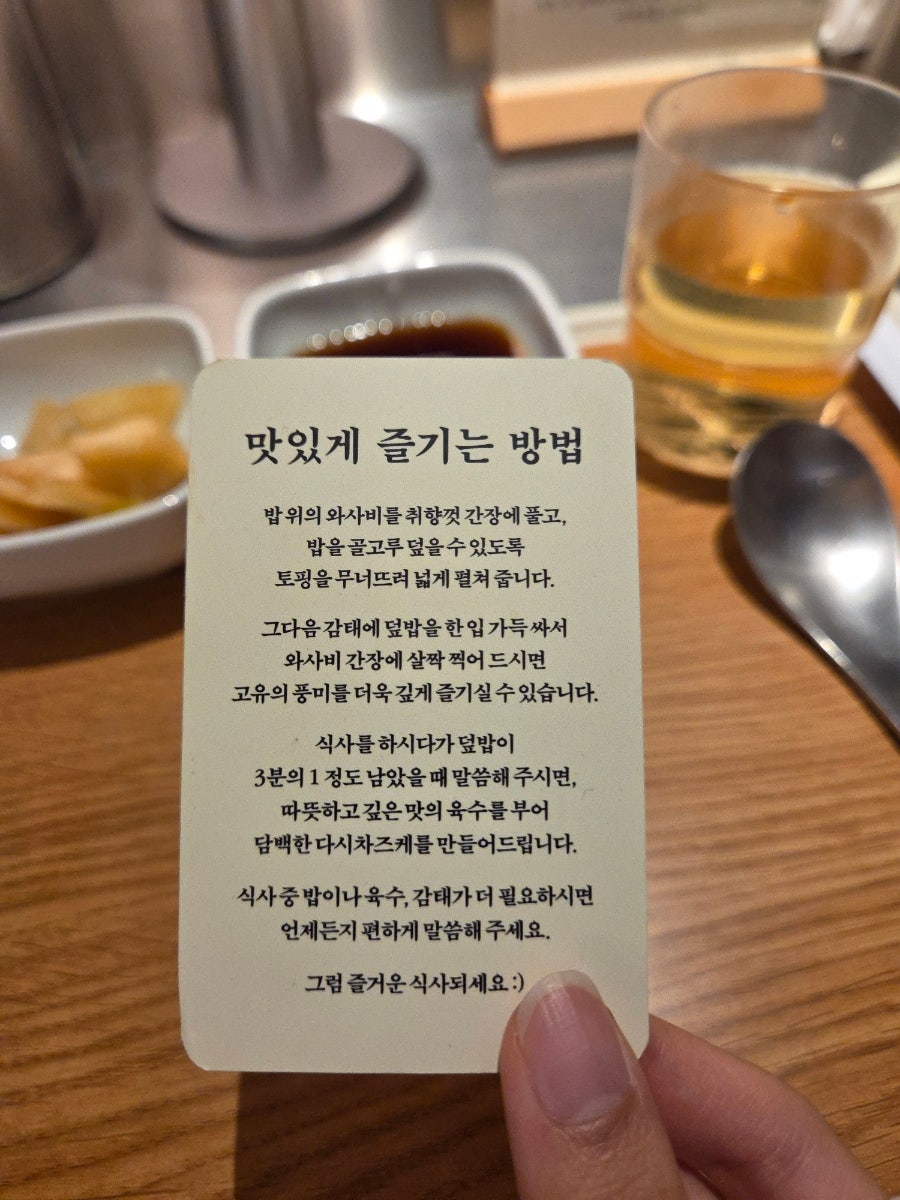 테이블에서 받은 '맛있게 즐기는 방법' 안내 카드입니다. 토핑을 펼쳐 감태에 싸 먹다가 밥이 3분의 1 남으면 육수를 부어 달라고 요청하라는 설명이 적혀 있습니다.