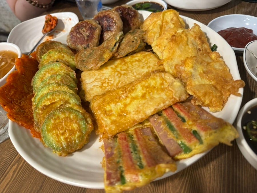 신당동 골목의 저녁 시간. 오래된 가게들의 불이 하나둘 켜지고 사람들이 들어오는 모습. 1980년대의 활기가 새로운 형태로 되살아나고 있다.