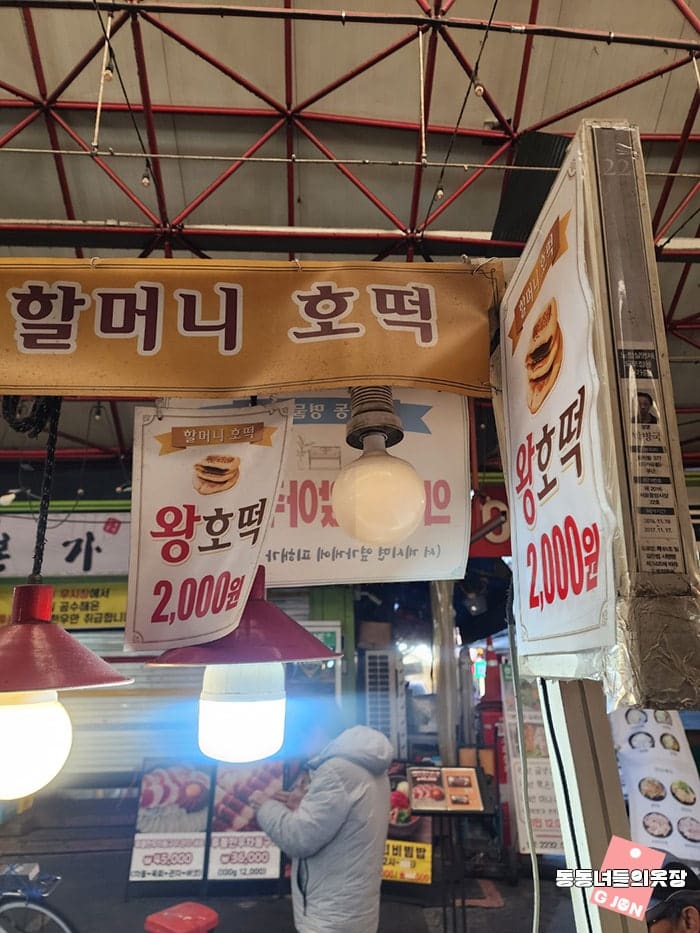 '할머니 호떡' 간판 아래 왕호떡 2,000원 팻말이 걸려 있고, 뜨거운 불빛 아래 사람이 줄지어 섭니다.