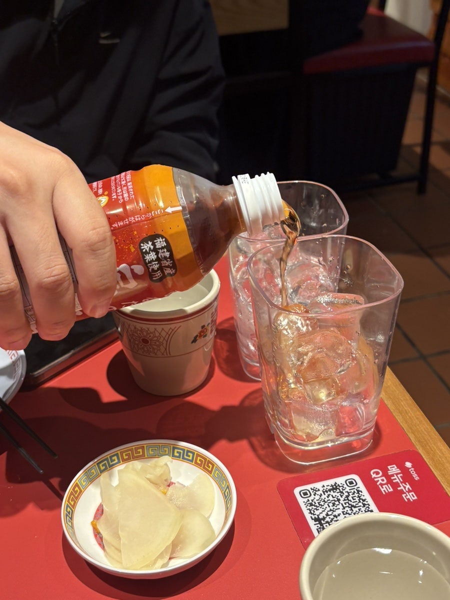 2strong_이 담은 매장 내부입니다. 테이블 간격이 넉넉한 붉은 좌석과, 술을 따르는 손길이 함께 보이는데 얼굴은 찍히지 않았습니다.