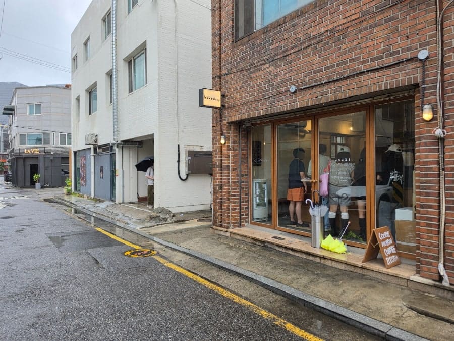 cloud0420이 찍은 비 오는 날의 매장 외관입니다. 붉은 벽돌 벽에 작은 'bakeshop' 간판이 걸려 있고,