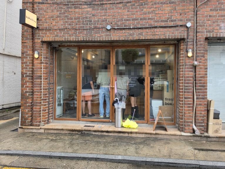 cloud0420이 찍은 비 오는 날의 매장 외관입니다. 붉은 벽돌 벽에 작은 'bakeshop' 간판이 걸려 있고,