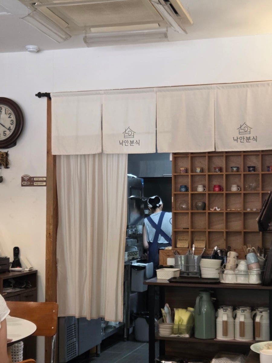 dnltjgml은 컷팅보드와 가방이 걸린 벽 선반을 담았고, hyunju0228은 '낙안분식' 글씨가 새겨진 포렴 너머로 분주한 주방을 찍었다.