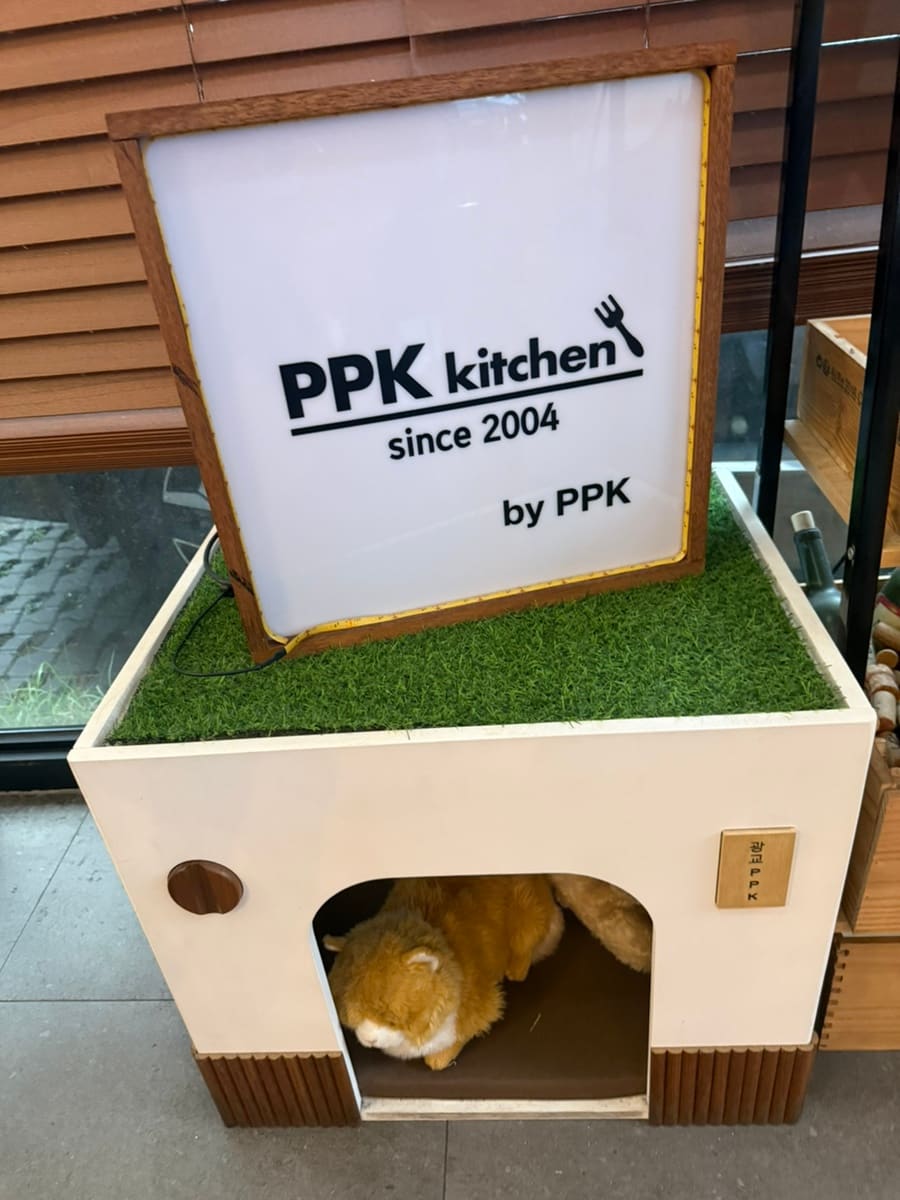 jjang2aa가 가족과 받은 식전빵과 수박, 그리고 매장 한쪽에 놓인 PPK 키친 브랜드 장식입니다.