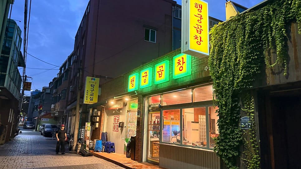 행궁곱창의 야간 외관. 초록색 네온 간판과 거리 조명이 어우러진 분위기
